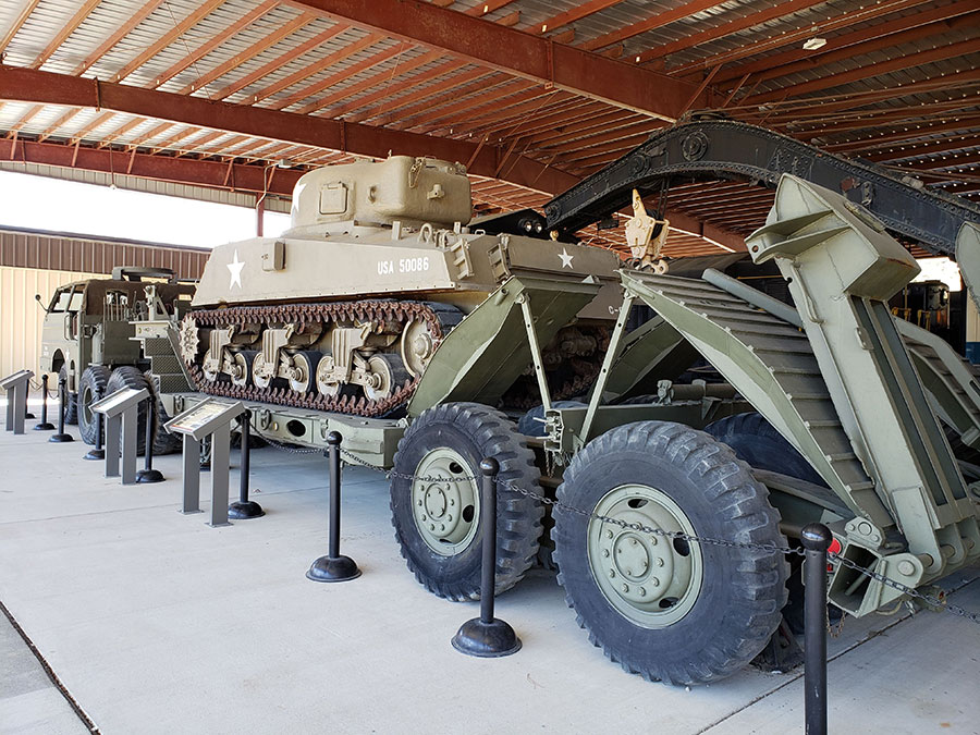 A US Army tank on top of a transporting vehicle as part of an exhibit at the US Army Transportation Museum.